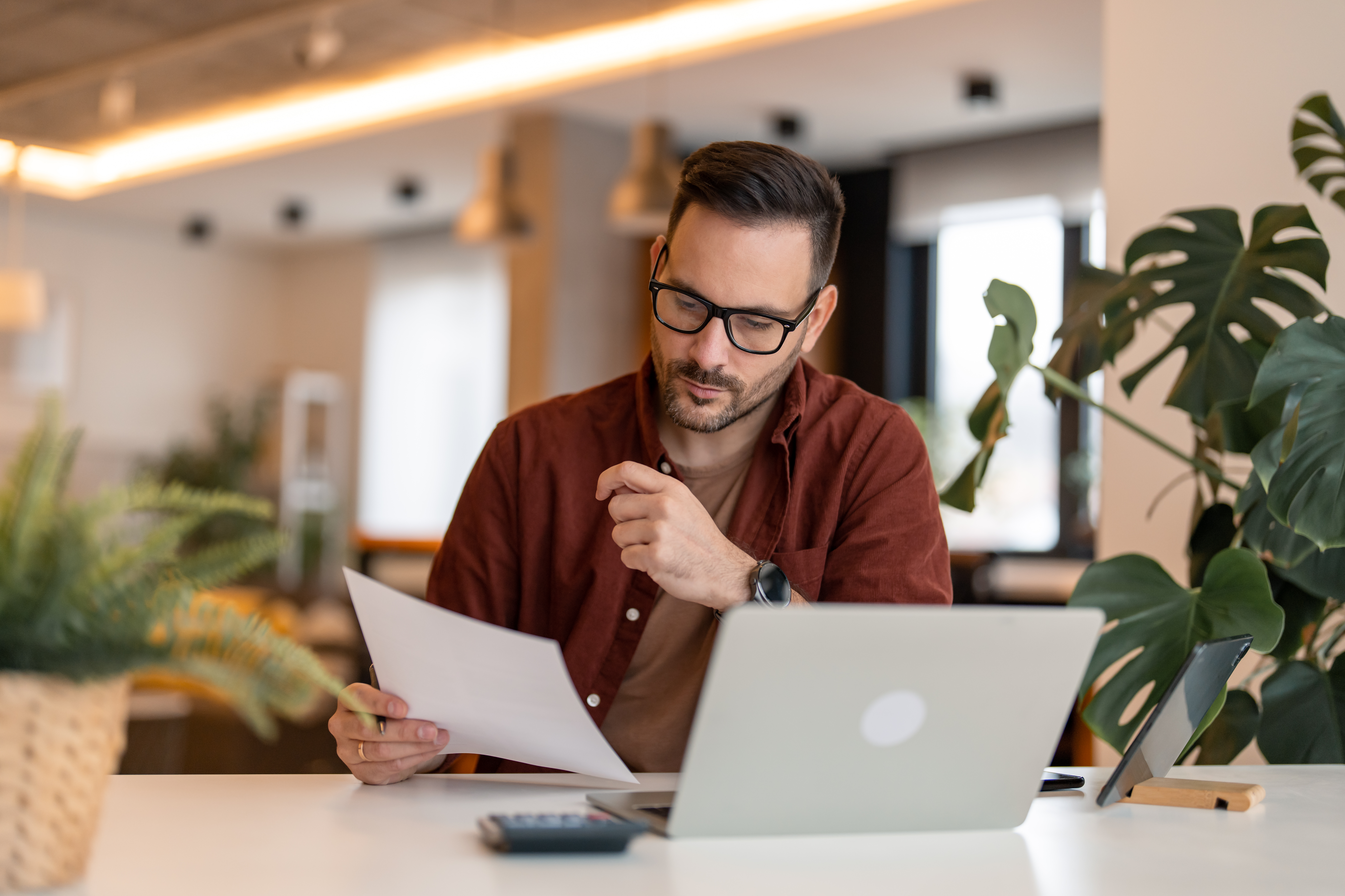 focused-man-with-glasses-reviewing-documents-at-desk.jpeg