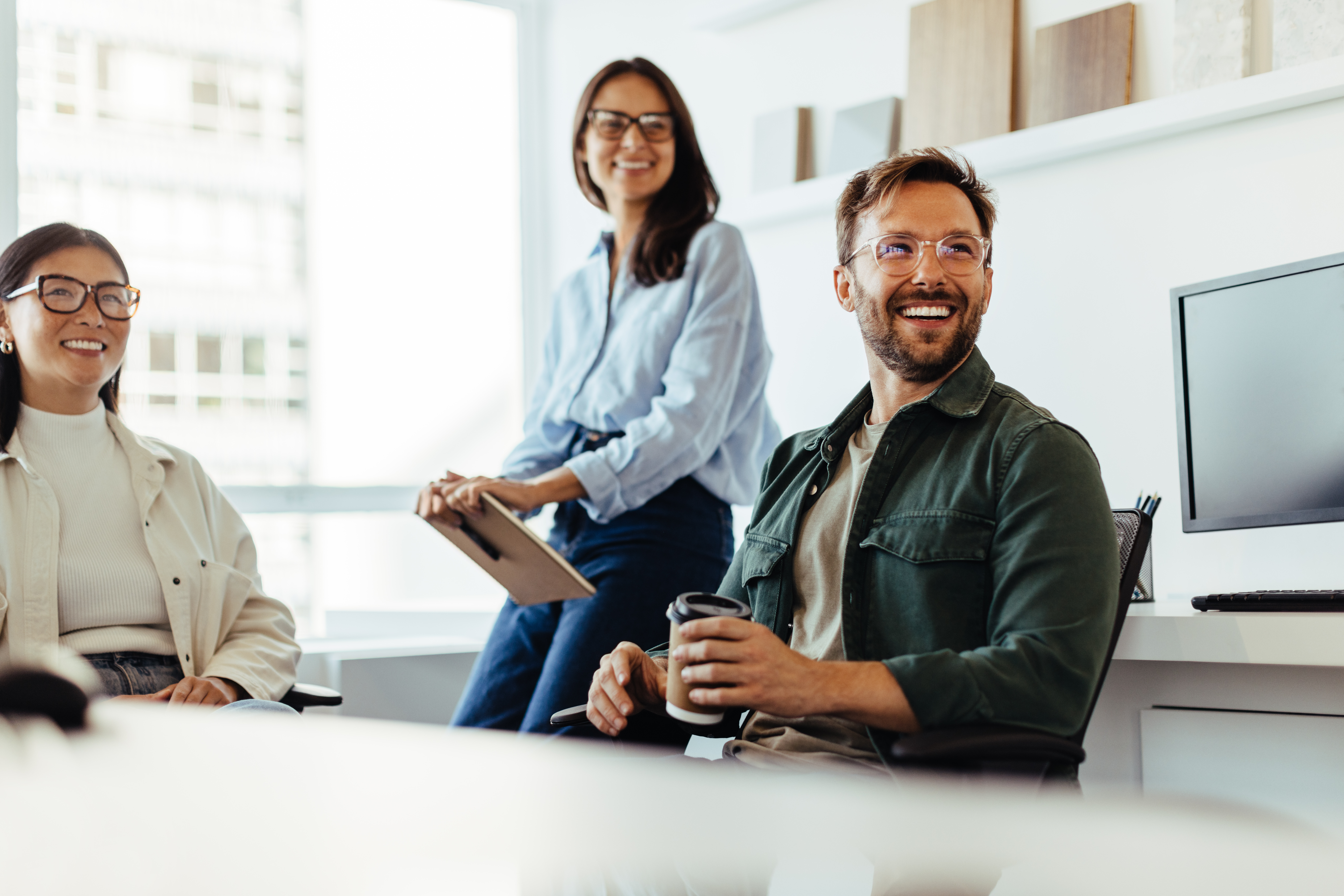 diverse-colleagues-smiling-with-coffee-in-bright-office.jpeg