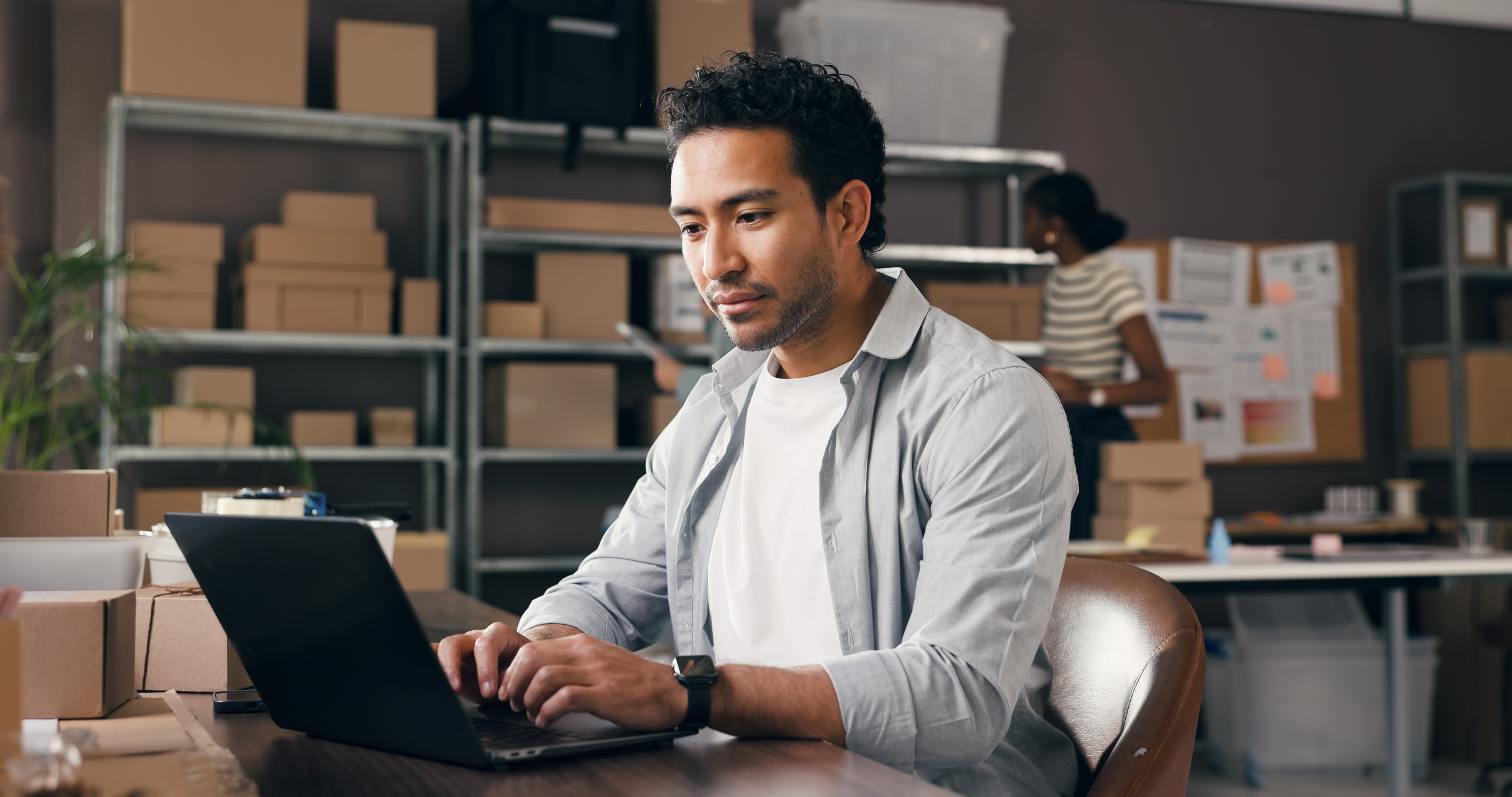 man-working-on-laptop-in-warehouse-with-shipping-boxes.jpeg