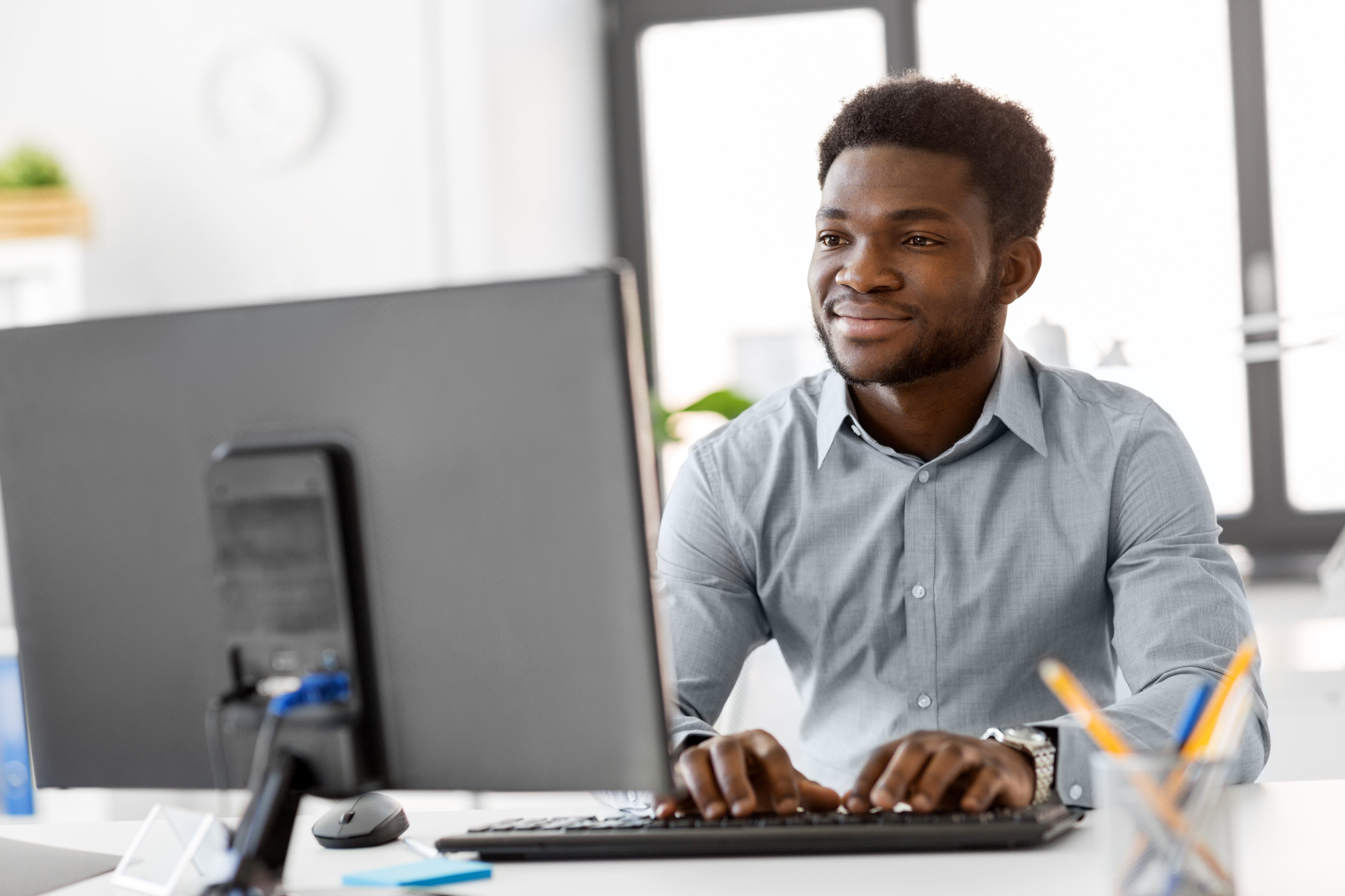 smiling-young-man-working-at-desktop-computer-in-office.jpeg