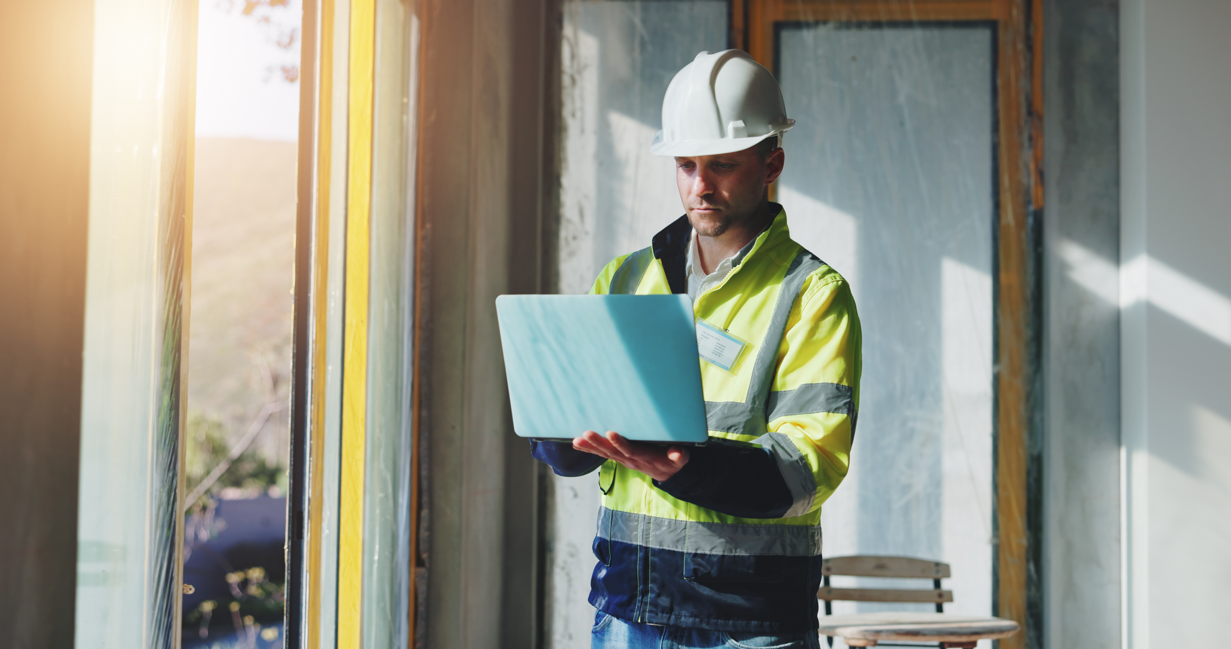 facilities-manager-reviewing-procurement-data-on-laptop-on-construction-site.jpeg