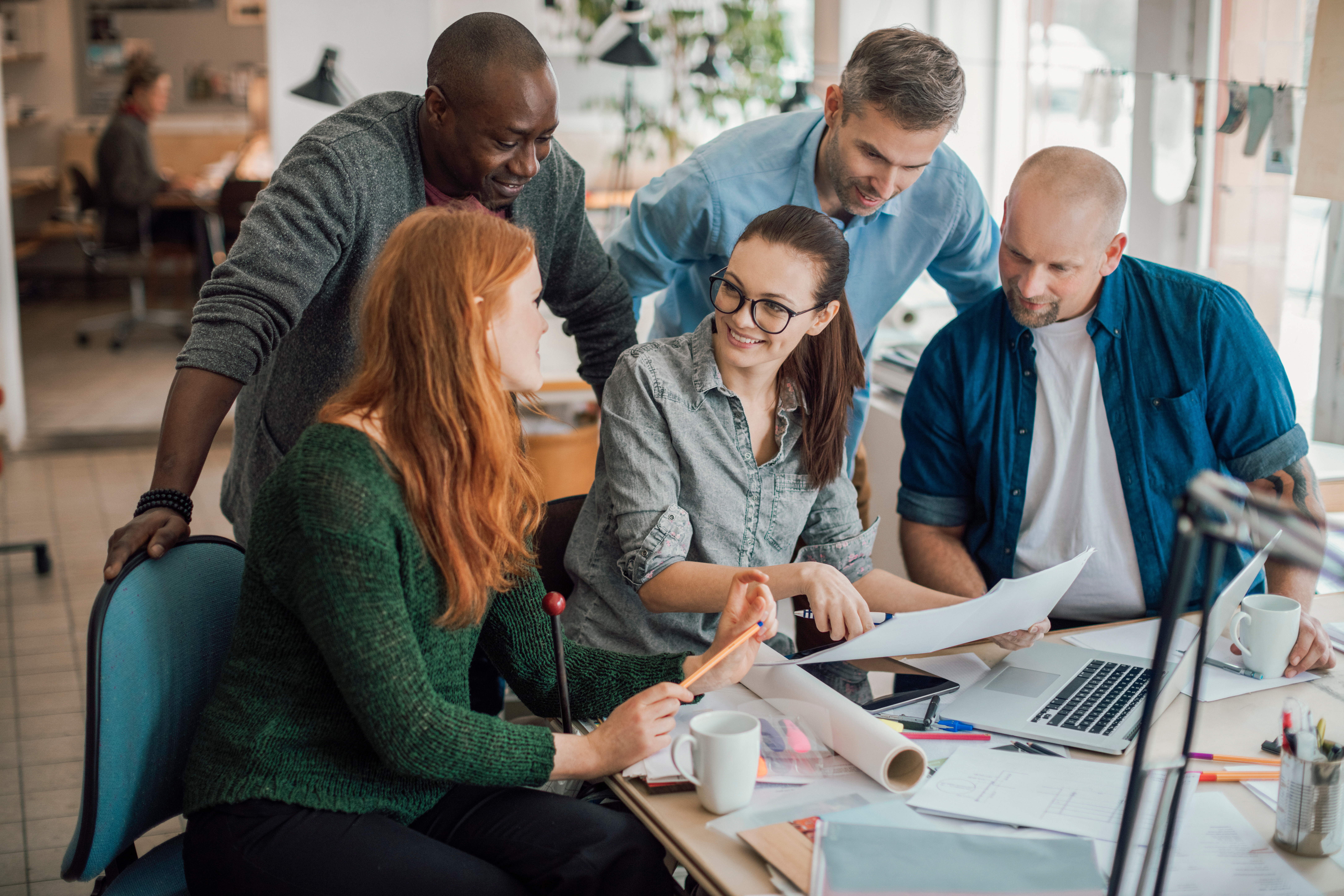 diverse-team-collaborating-over-documents-at-office-desk.jpeg