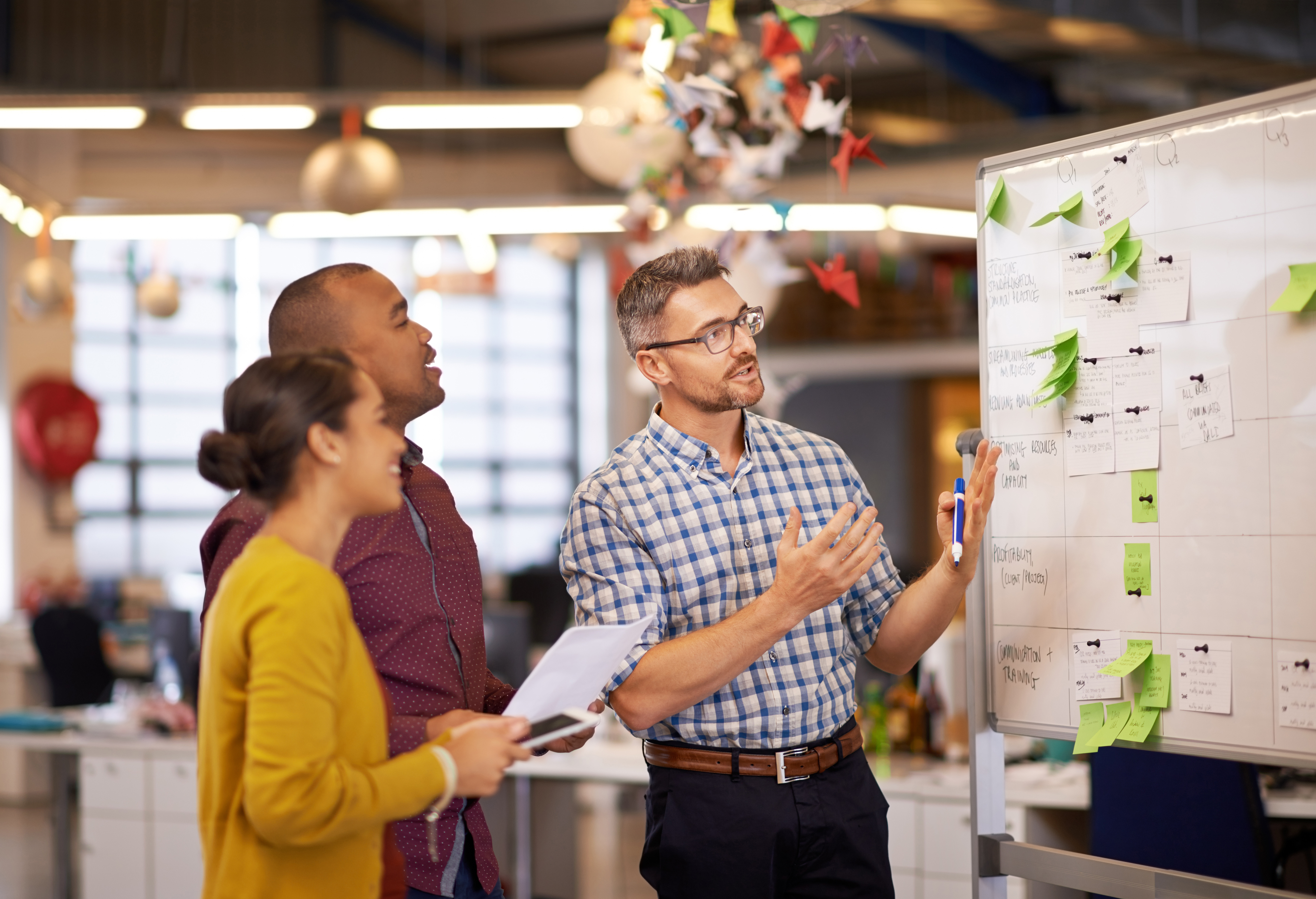 diverse-team-reviewing-sticky-notes-on-whiteboard-in-office.jpeg