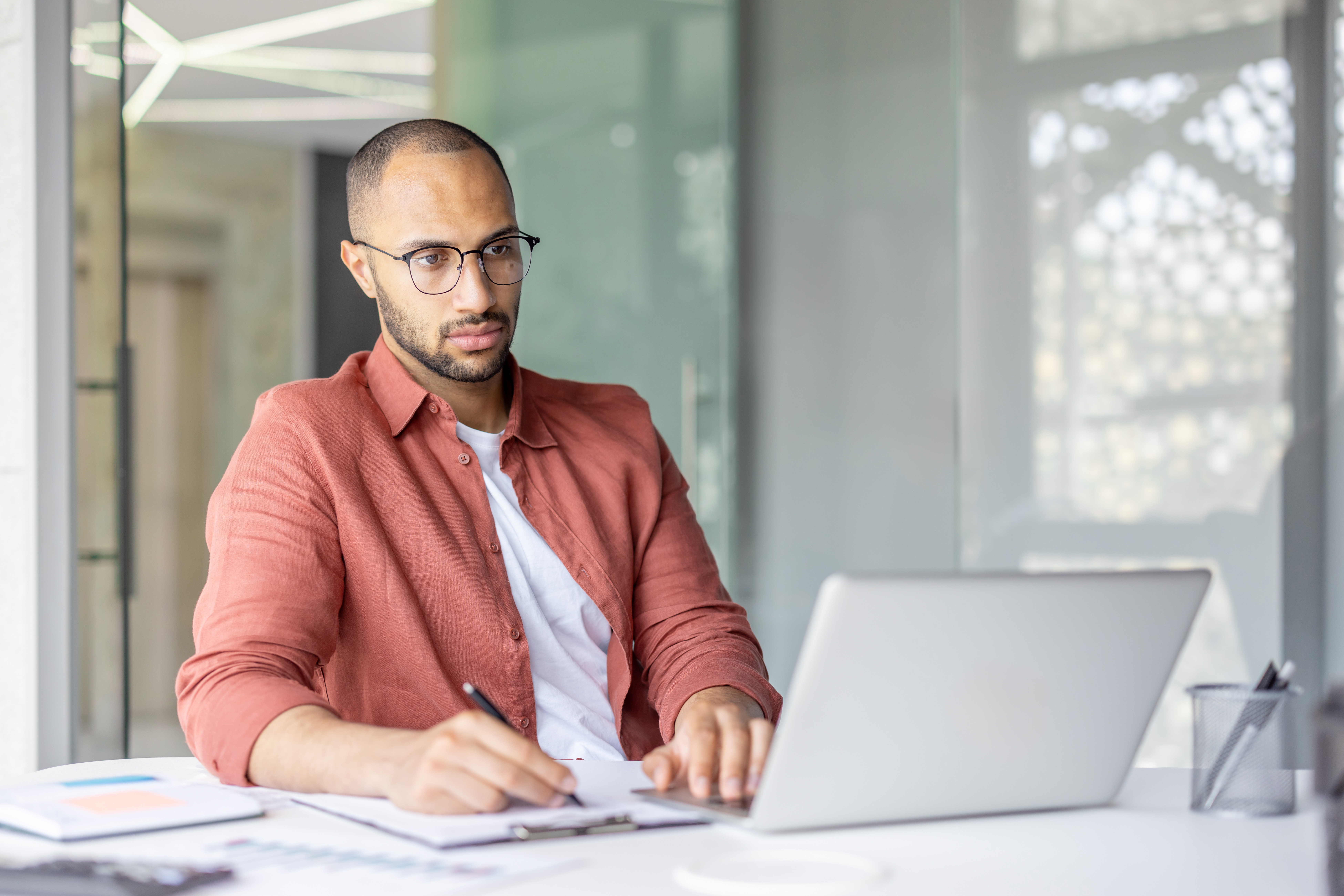 focused-man-with-glasses-working-on-laptop-at-office-desk.jpeg