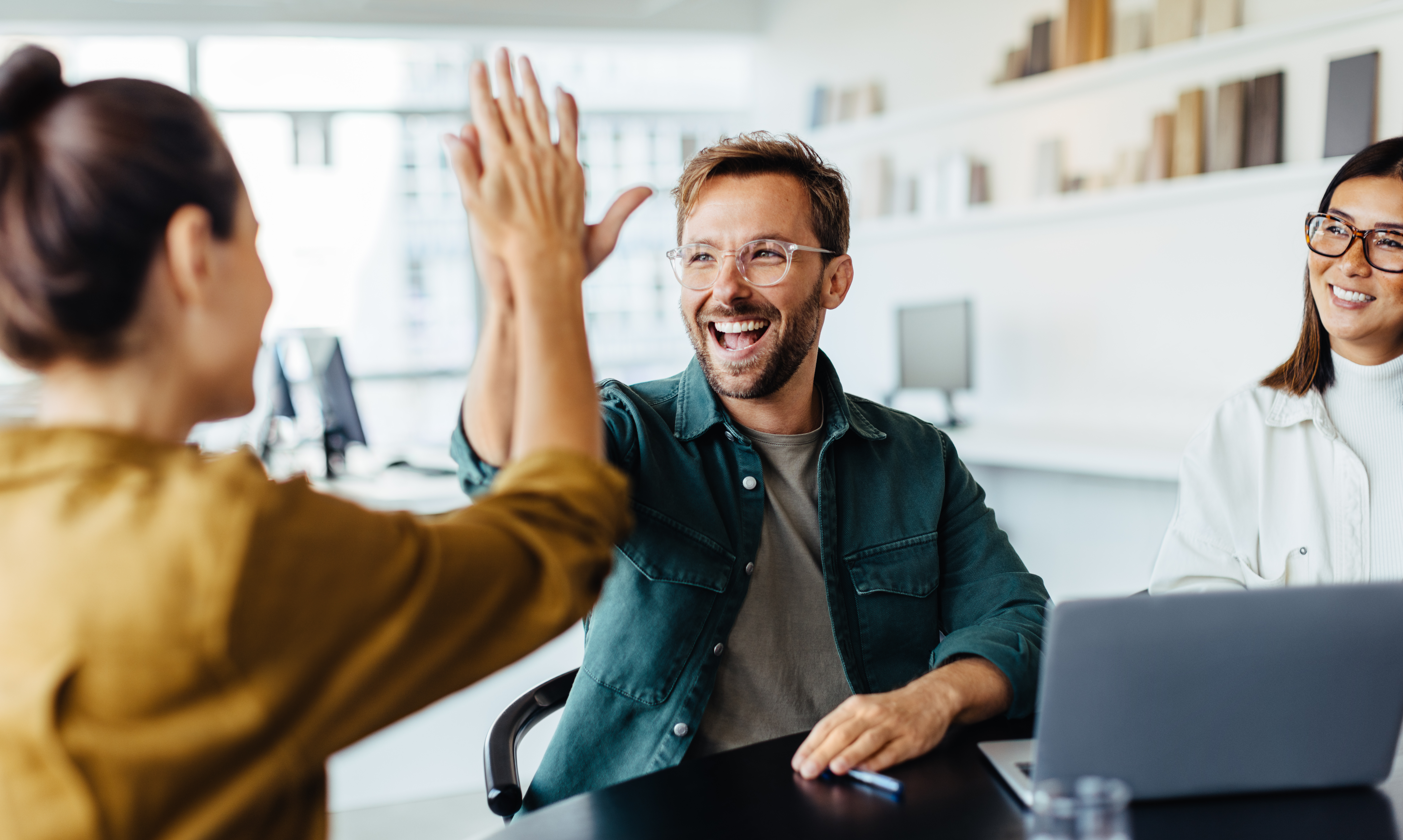 colleagues-giving-high-five-at-office-meeting-table.jpeg