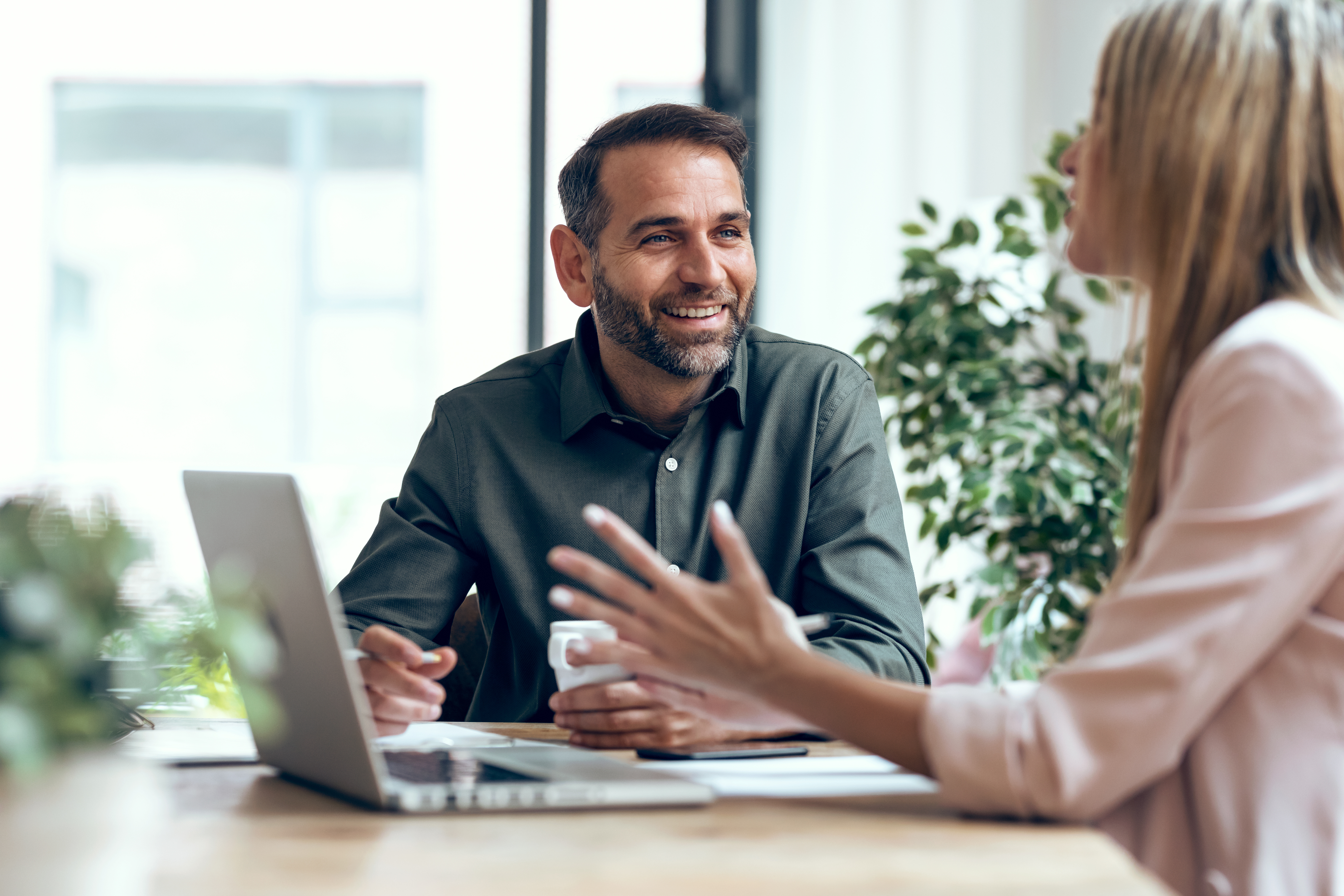 smiling-bearded-man-talking-with-colleague-over-laptop.jpeg