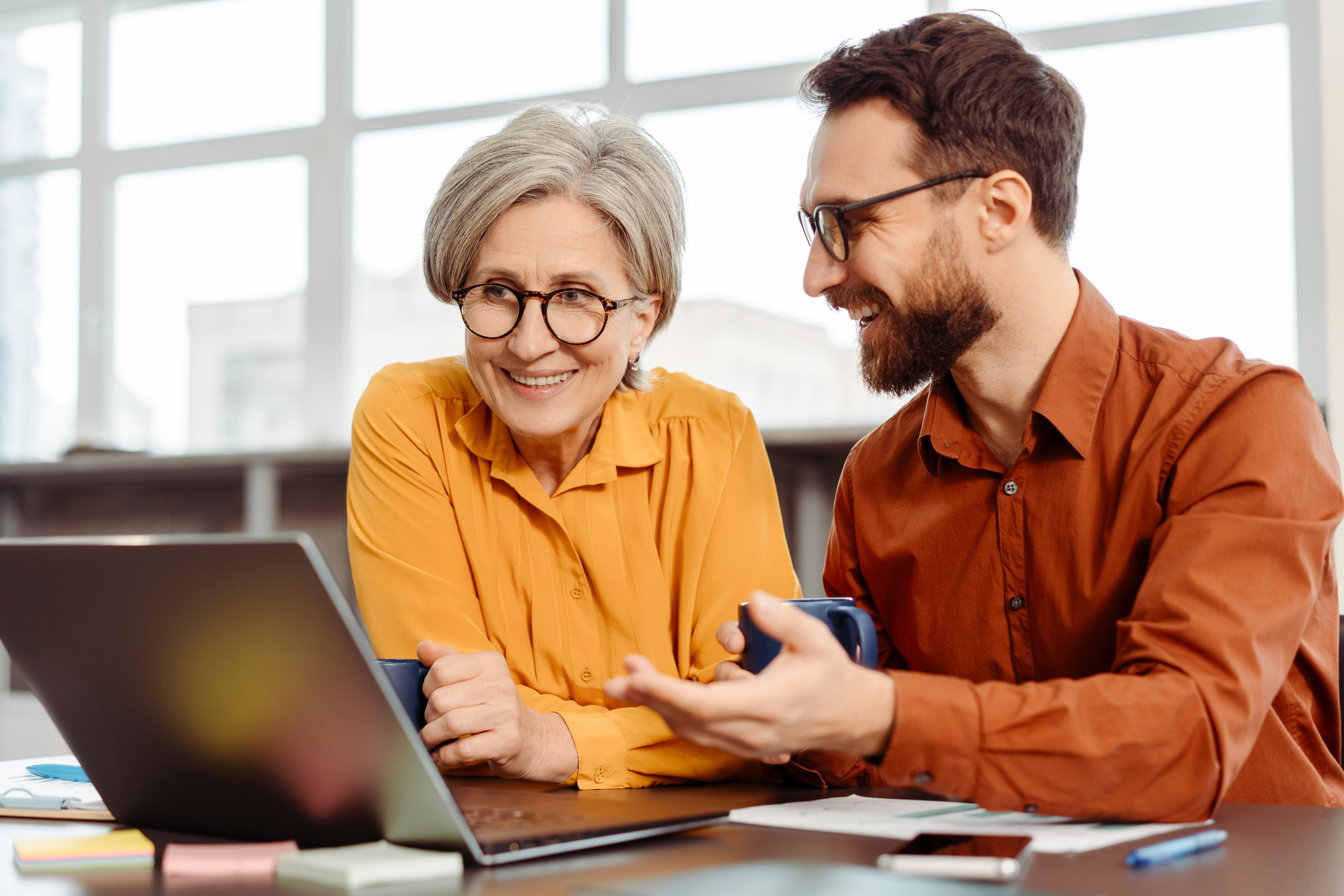 senior-woman-and-man-colleagues-discussing-over-laptop.jpeg