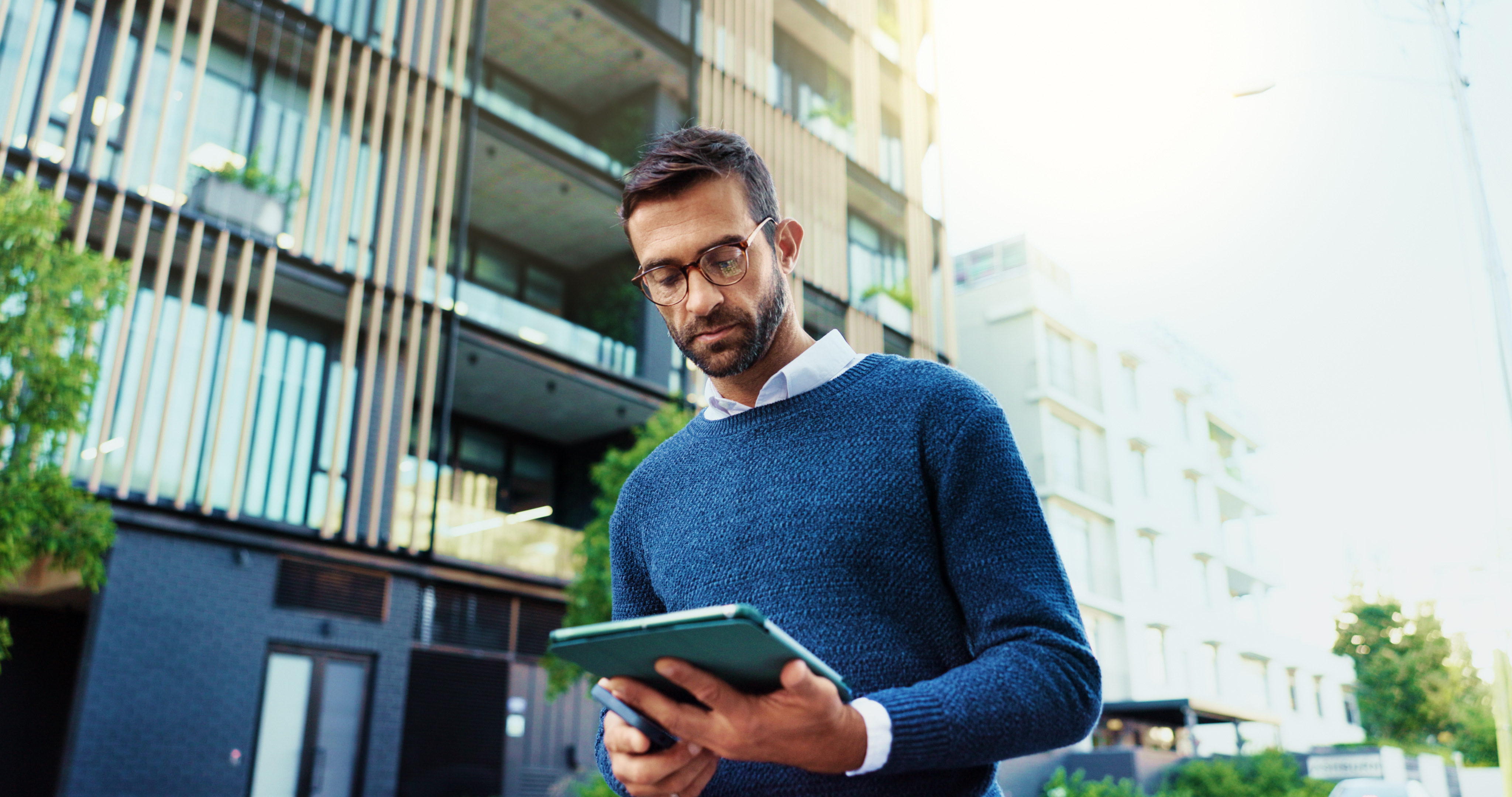 housing-procurement-manager-reviewing-contracts-on-tablet-outside-apartments.jpeg