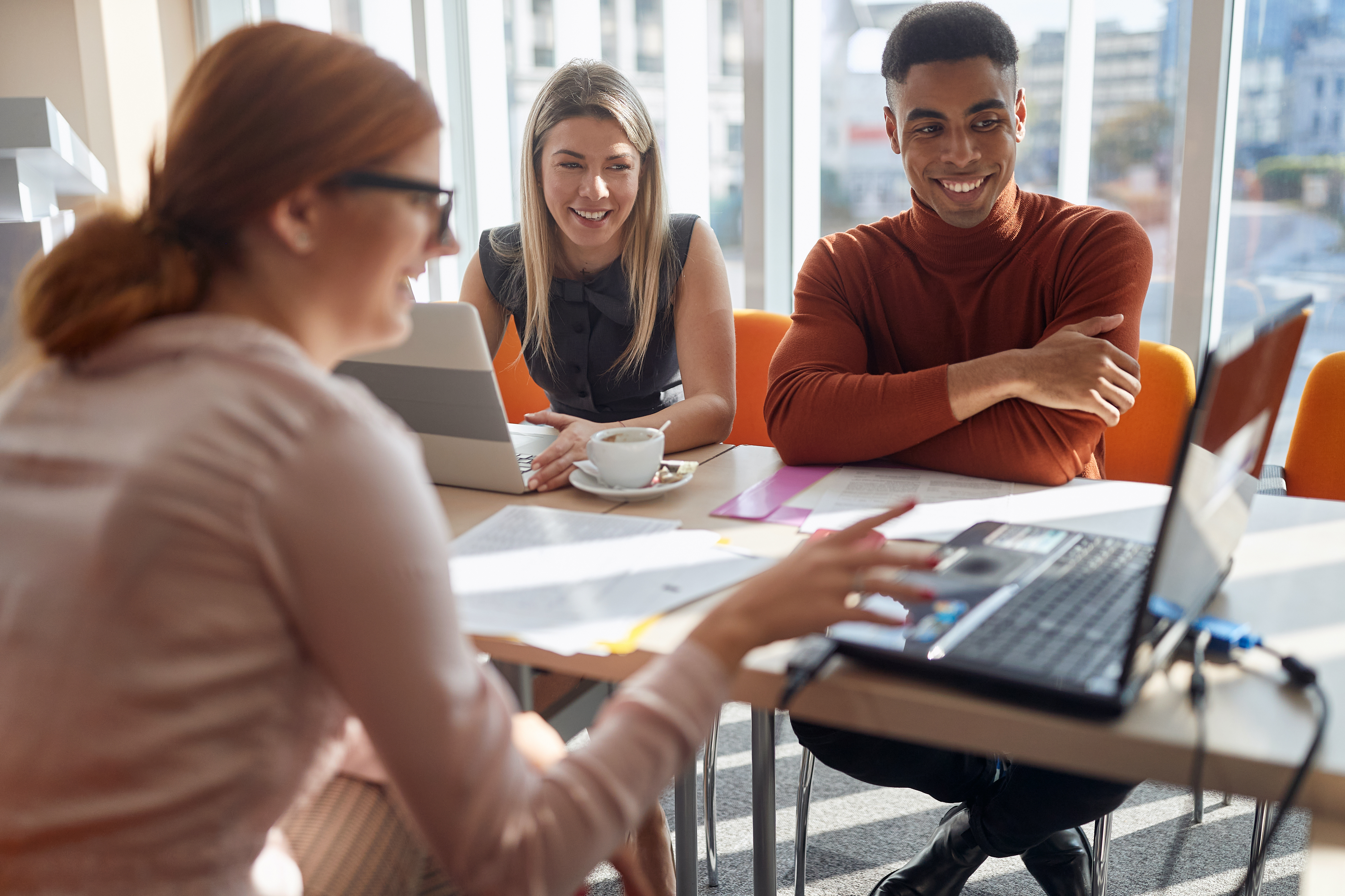 diverse-colleagues-smiling-and-talking-at-meeting-table.jpeg