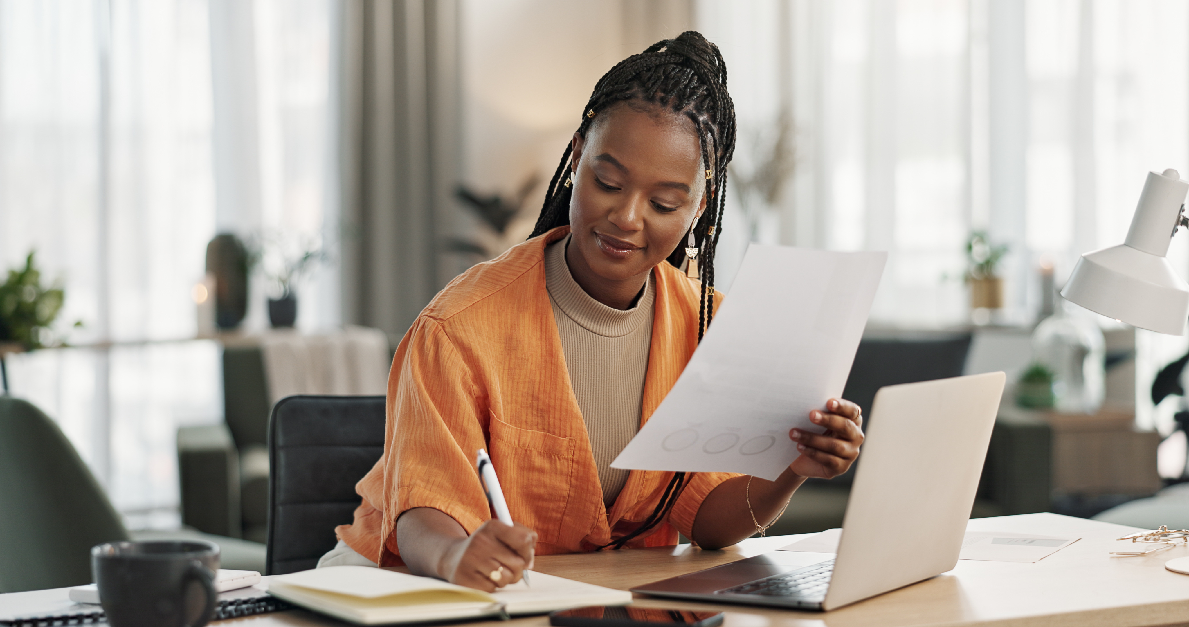 woman-reviewing-documents-and-writing-notes-at-home-desk.jpeg