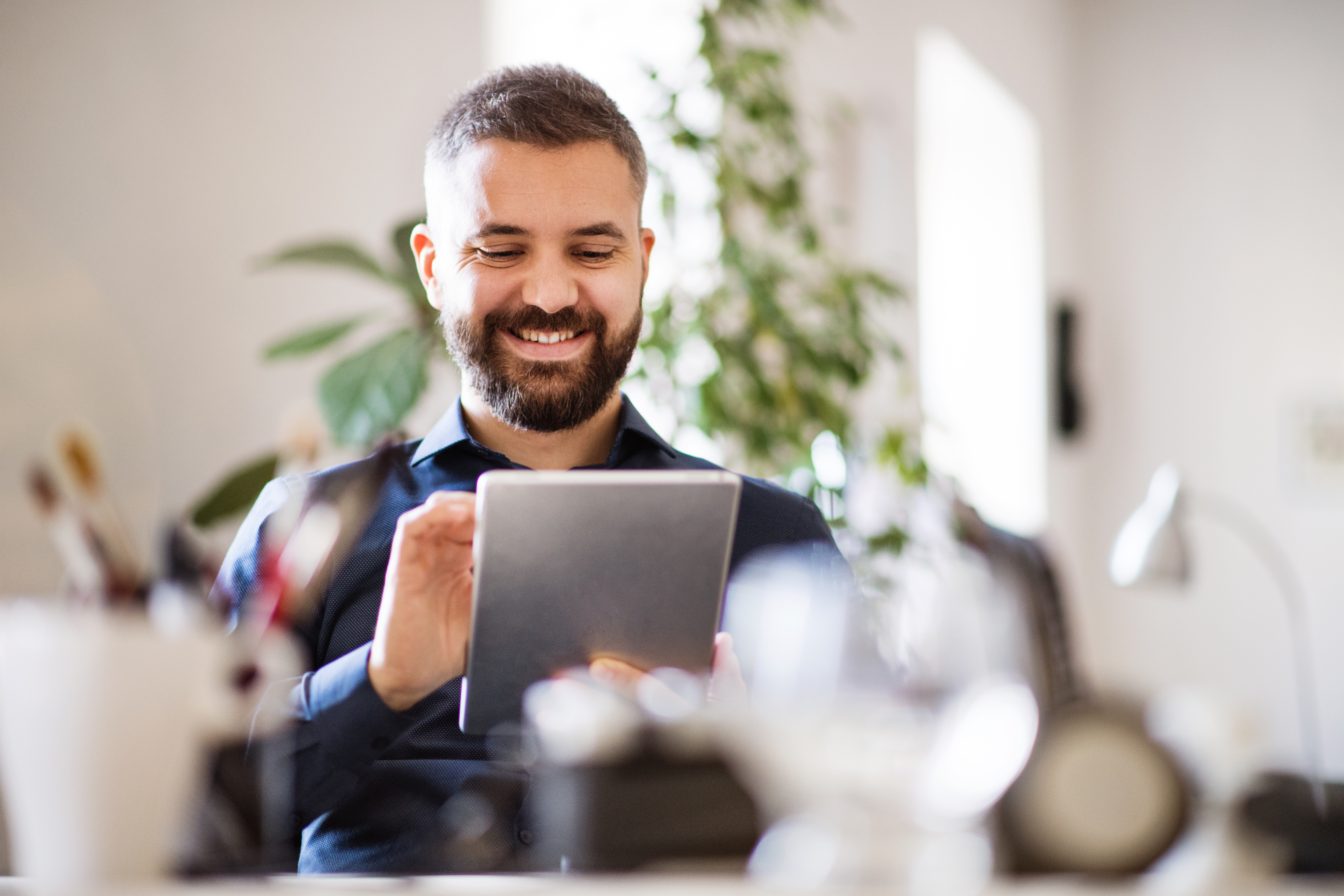 smiling-bearded-man-holding-tablet-in-home-office.jpeg