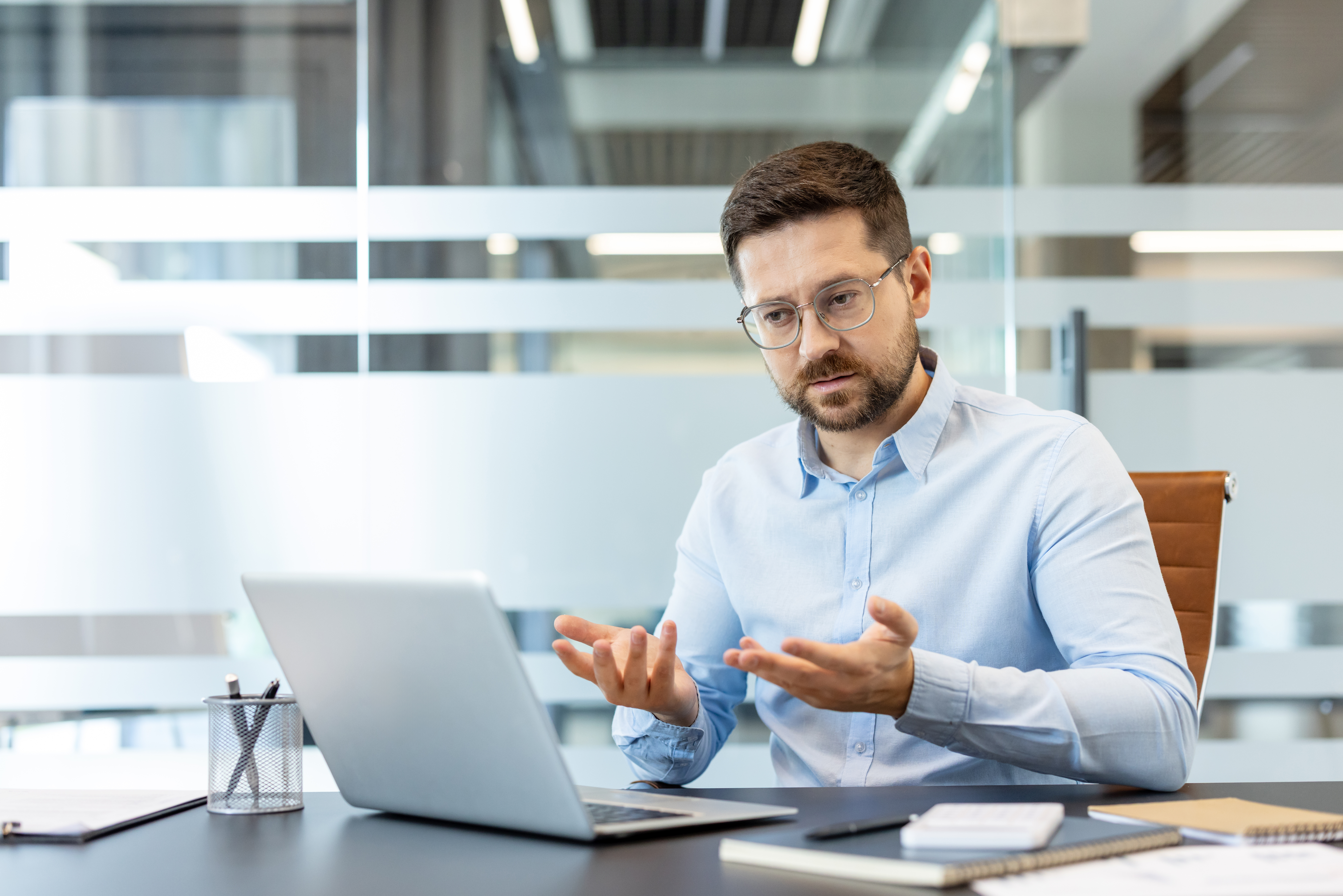 businessman-with-glasses-on-video-call-at-office-desk.jpeg