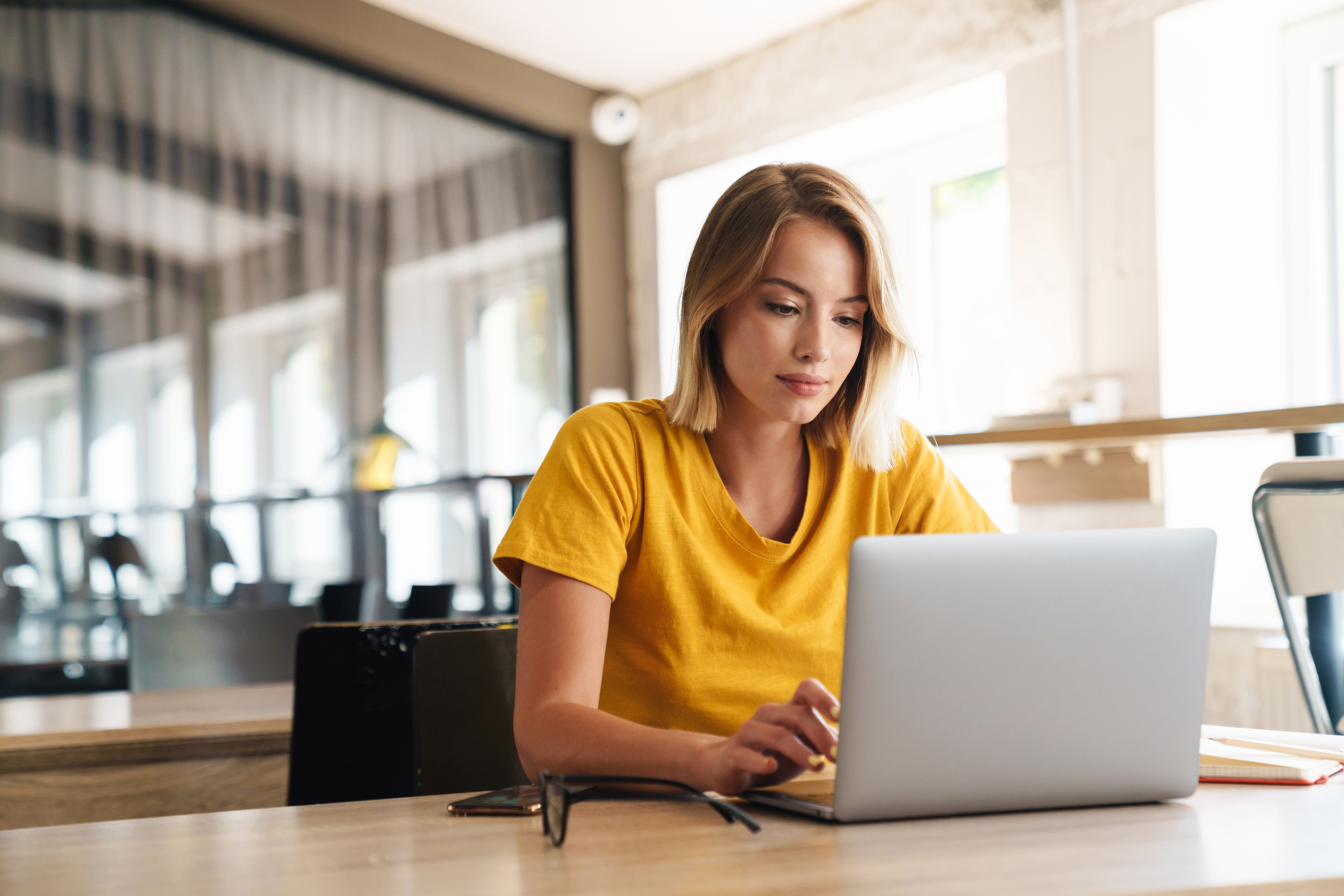 young-woman-in-yellow-top-working-on-laptop-in-cafe.jpeg