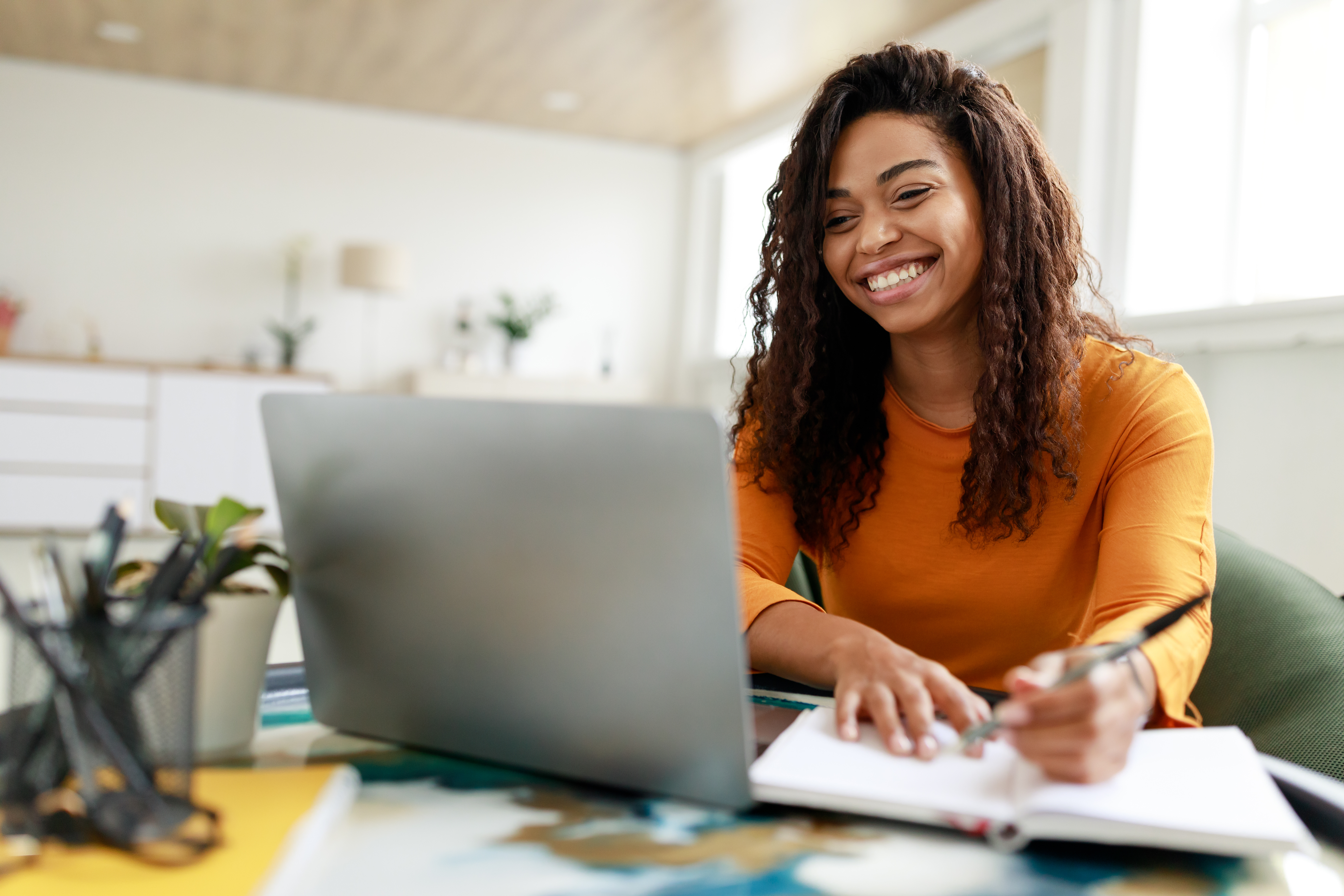 happy-young-woman-using-laptop-and-taking-notes-at-home.jpeg